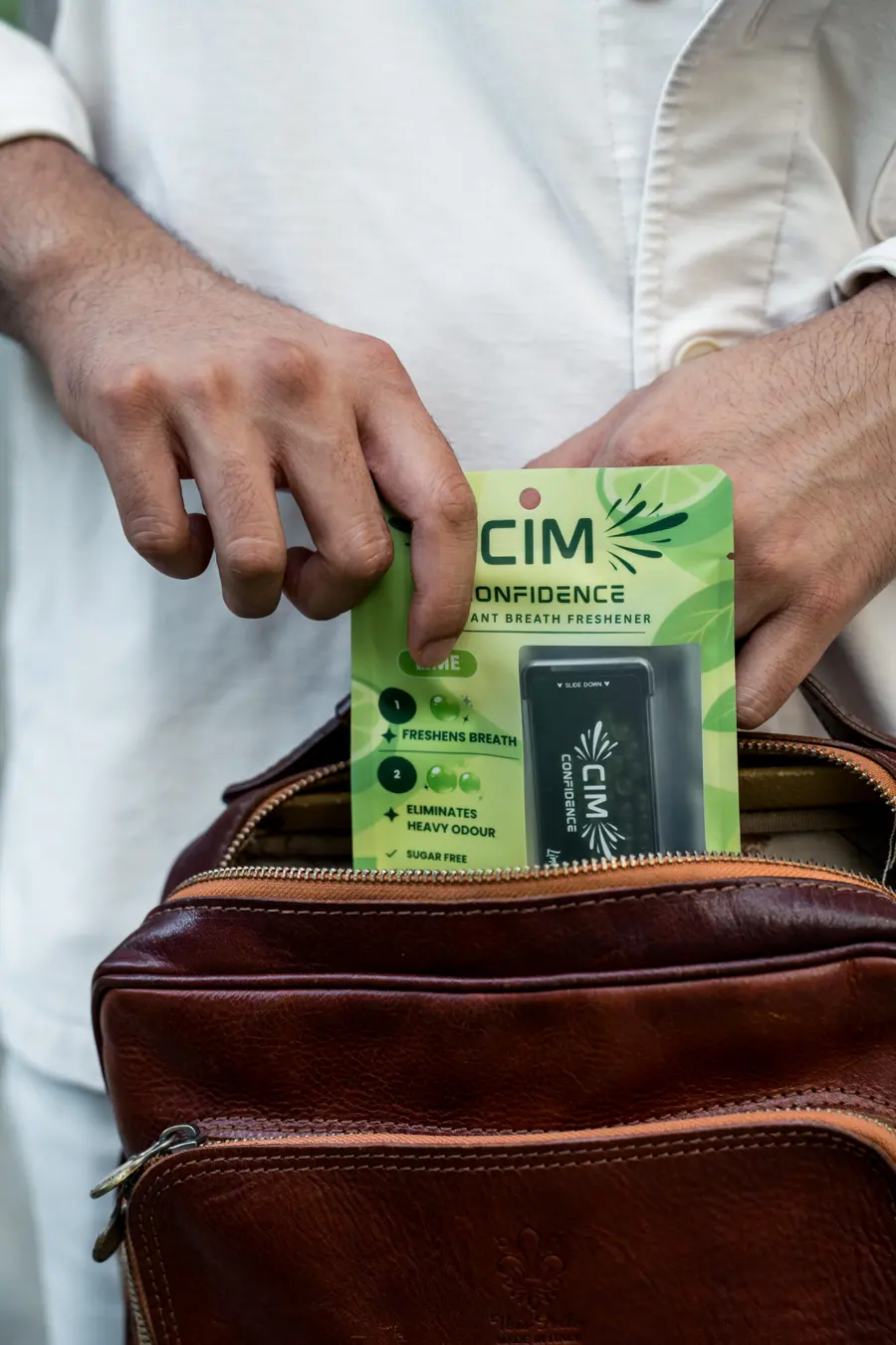 A lime CIM retail pack being placed into a leather bag