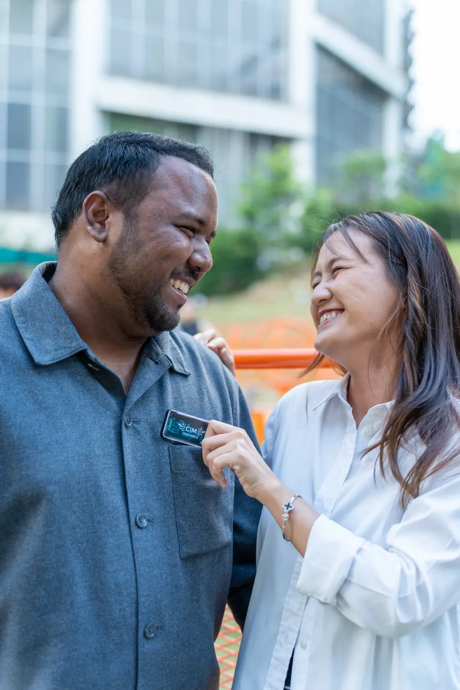 A woman tucking a CIM case into a friend's shirt pocket, both laughing